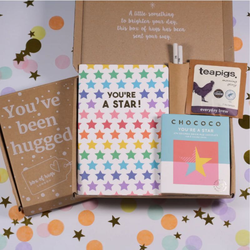 Gift box with 'You're a Star!' notebook and other items on a colorful star-patterned background