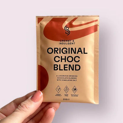 Hand holding a 'Original Choc Blend' package against a light purple background