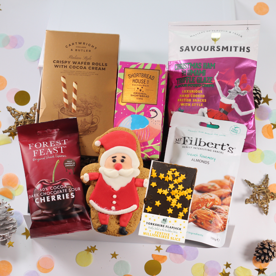 Assorted Christmas-themed food hamper with santa gingerbread, chocolate cherries, shortbread, flapjack, almonds and wafer rolls.