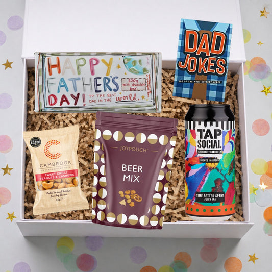 Gift box with Father's Day card, snacks, and a beer can on a colorful polka dot background