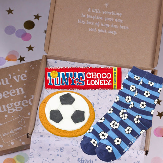Box of 'hugs' with Tony's Choco Lonely, a cookie, and a pair of socks on a colorful background.