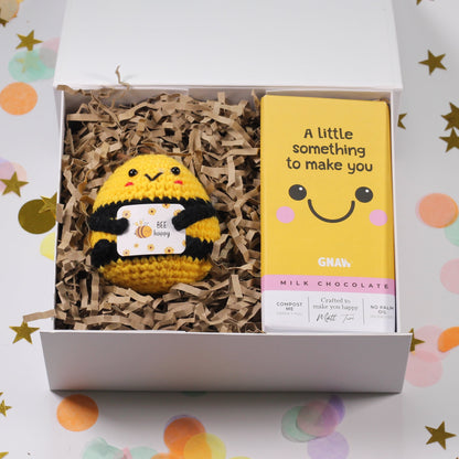 Gift box with a crochet bee plush toy and a card on a confetti background