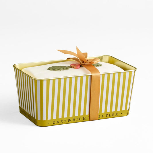A rectangular metal gift box with vertical yellow and white stripes, tied with a peach ribbon and bow, on a clean white background. The bottom edge reads 'CARTWRIGHT BUTLER'.