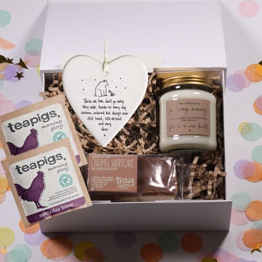 bereavement Gift box with teapigs tea, a 'in loving memory candle, a those we love dont go away ceramic heart plaque and chocolate caramel shortcake on a colorful polka dot background