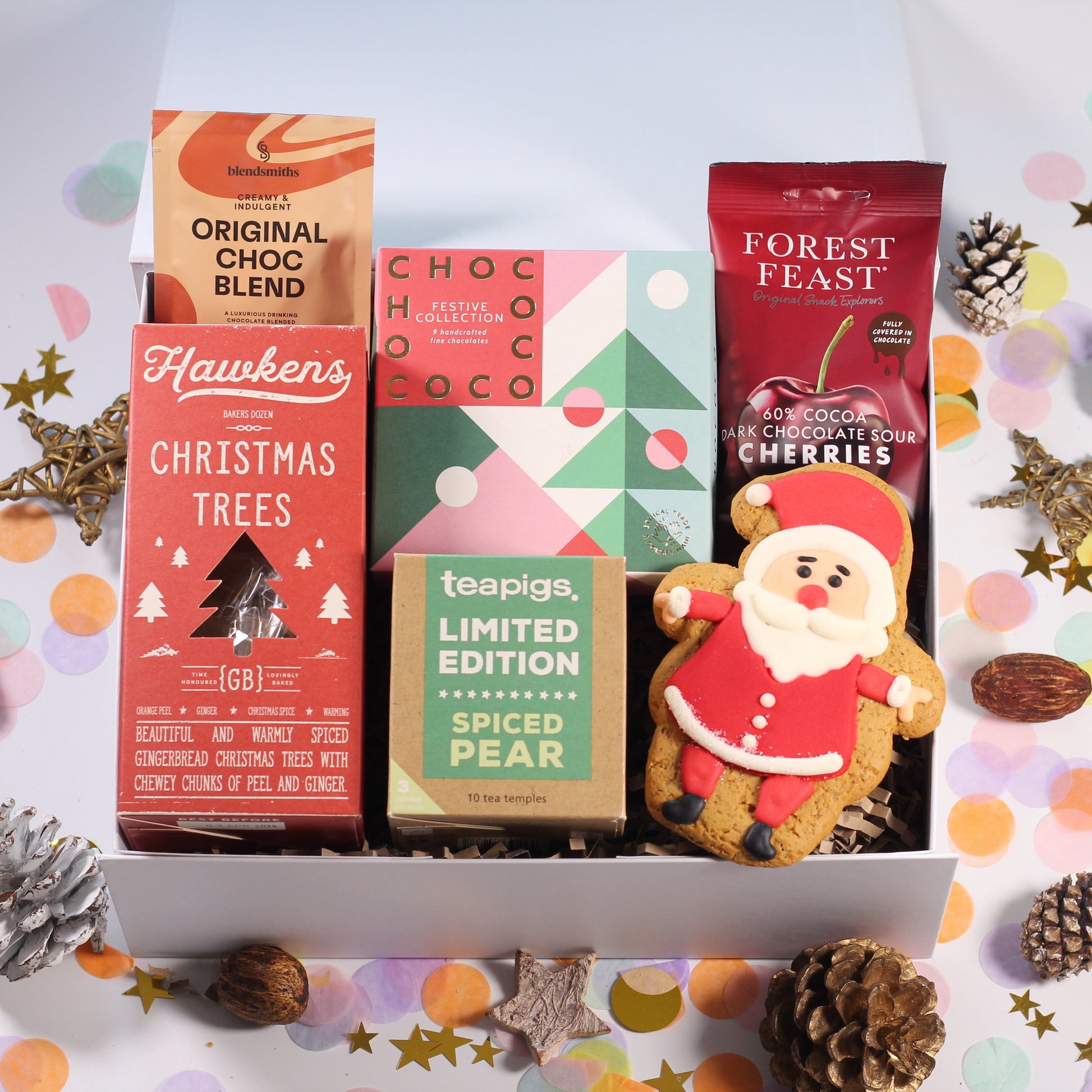 Christmas gift box filled with assorted Christmas-themed products including tea bags, Santa Claus gingerbread biscuits, chocolate cherries, festive box of chocolates, hot chocolates and gingerbread Christmas trees.