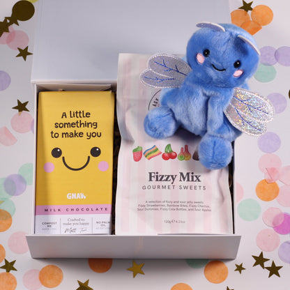 A white keepsake magnetic box with a blue plush dragonfly toy, a yellow chocolate bar labeled 'A little something to make you smile', and a 'Fizzy Mix Gourmet Sweets' pouch.