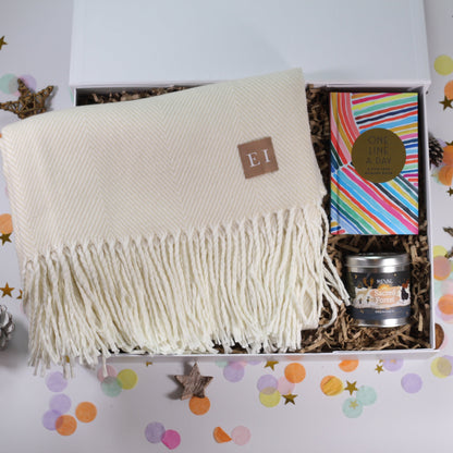 Gift box with a cosy white blanket, beautiful St Eval Sacred Forest candle, and a brightly coloured 'one line a day' journal.