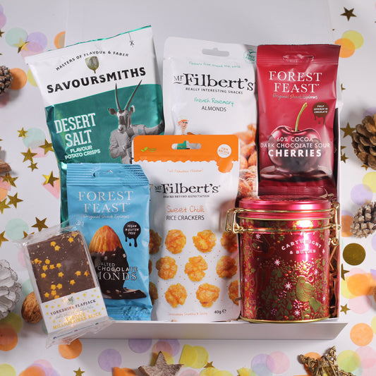 Christmas gift box with Assorted christmas snacks including Christmas tin of fudge, Savoursmiths crisps, Mr Filbert's almonds amd chilli crackers, and Forest Feast chocolate almonds and cherries and festive flapjack.