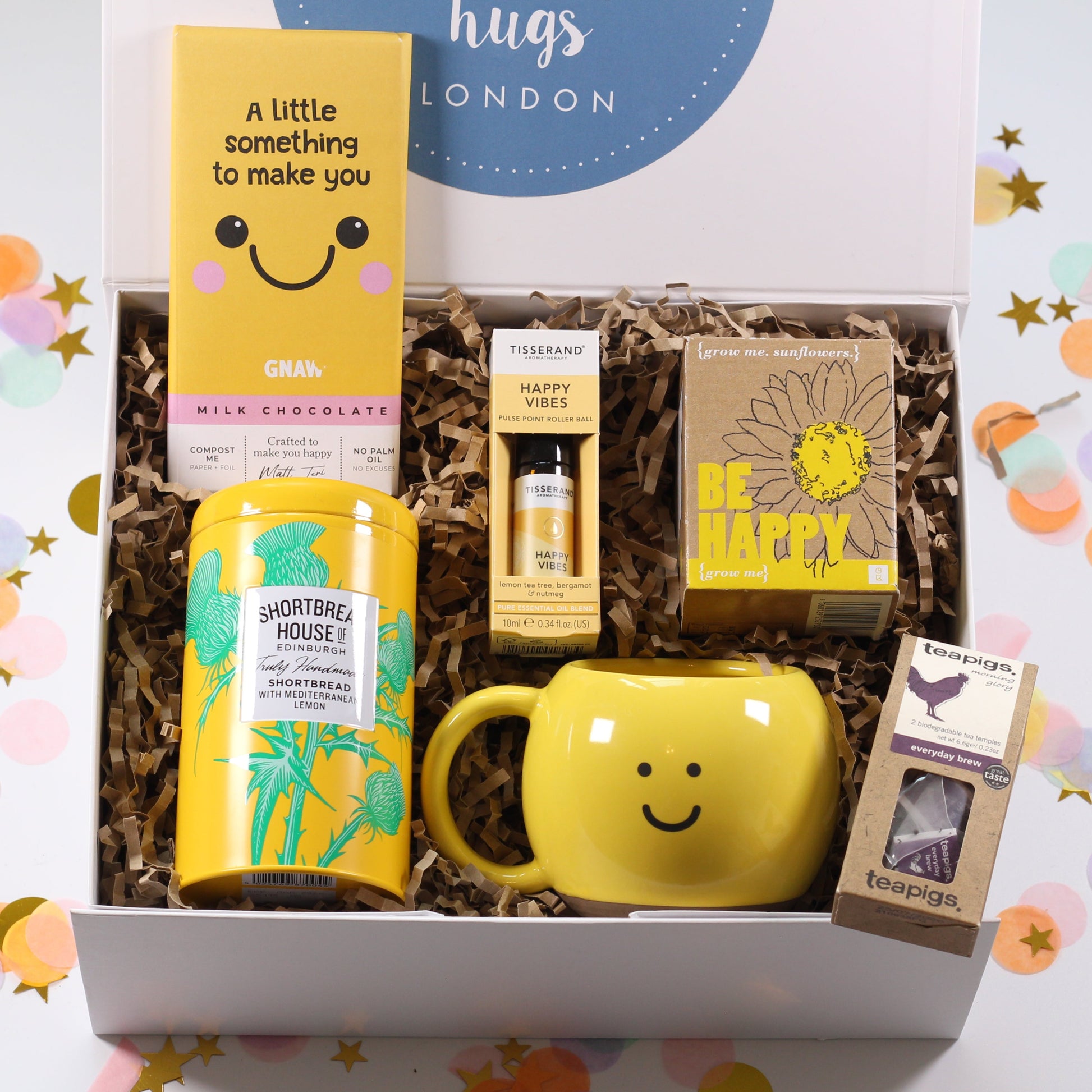 Gift box with a yellow happy smile mug, smile chocolate bar, happy roll on, be happy grow your own sunflower, lemon shortbread biscuit and tea.