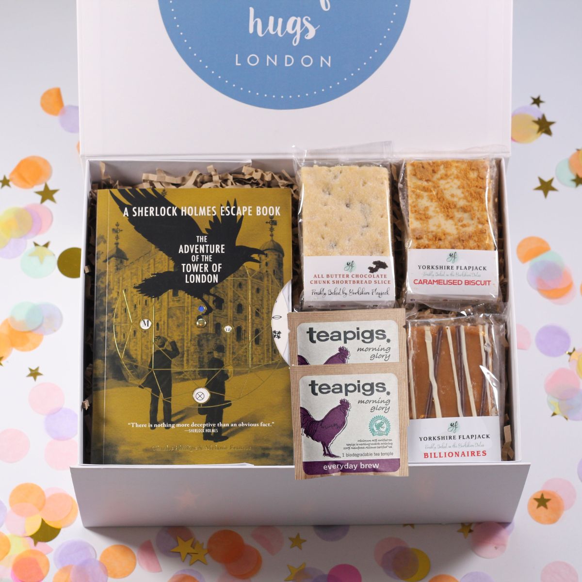 Gift box with Sherlock Holmes book, teapigs tea, and flapjack and shortbread on a colorful confetti background