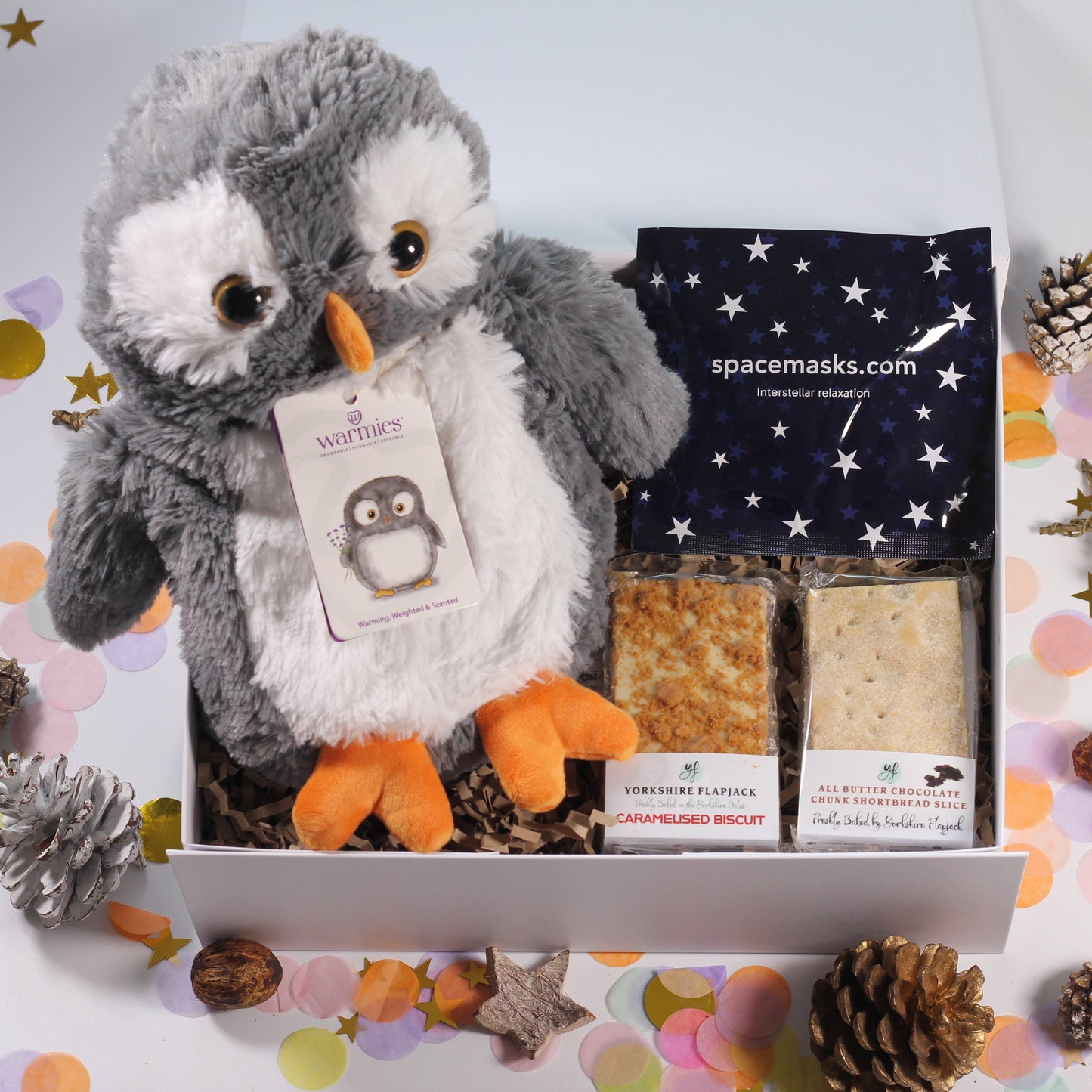 Gift box with Warmies plush penguin, self heating eye space mask, biscoff flapjack and chocolate chunk shortbread.