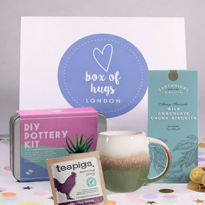 DIY pottery kit, teapigs tea bag, and chocolate biscuits with 'Box of Hugs London' branding.