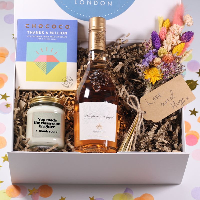 Gift basket with a bottle of rose wine, candle, and flowers on a colorful background