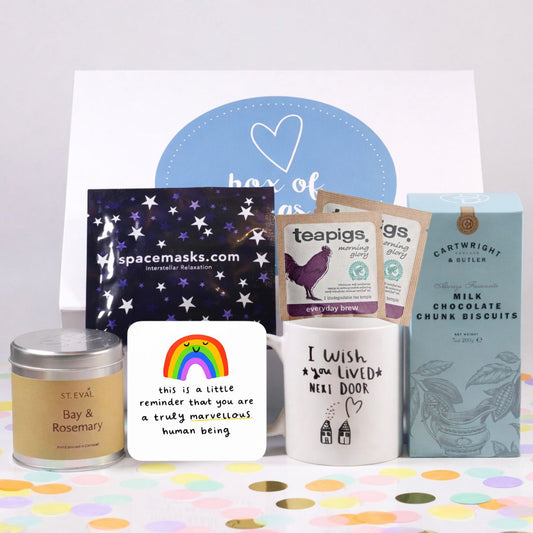 Collection of items including a candle, an uplifting coaster, chocolate chunk biscuits, tea and heated eye mask on a colorful background