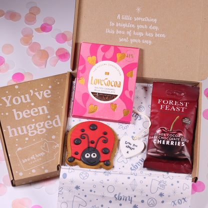 Gift box with 'You've been hugged' card, LoveCocoa chocolate, and Forest Feast dark chocolate cherry package on a decorative background.