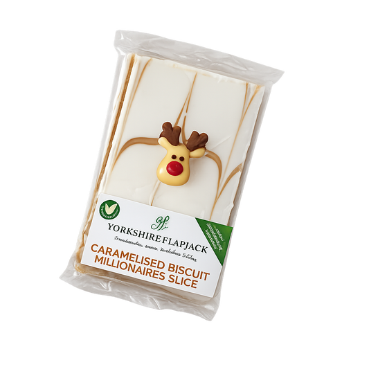 A packaged slice of Yorkshire Flapjack Caramellised Biscuit Millionaires Slice, featuring white icing with a reindeer decoration on top, sealed in a clear plastic bag with a white and green paper label.