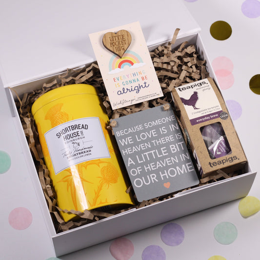 A white keepsake magnetic box with a selection of items including a metal sign, a tin of shortbread biscuits, a pocket hug keepsake token, tea temples, and a card with a personal message.