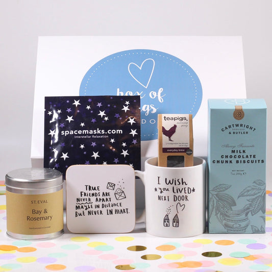 A collection of gift items including a candle, spacemask, tea, mug, and biscuits, packaged in a white box with a keepsake coaster  that reads 'True Friends Are Never Apart'.